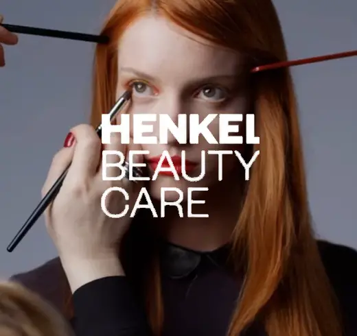 Henkel logo next to woman doing make up